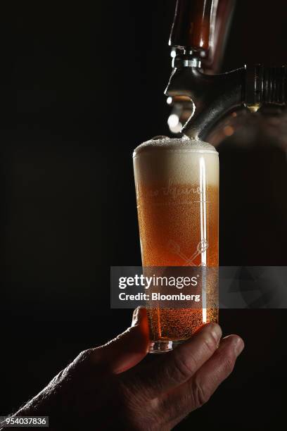 Glass of James Squire Hop Thief American pale ale is poured from a beer tap at The Malt Shovel Brewery, operated by Lion Pty Ltd., in Sydney,...