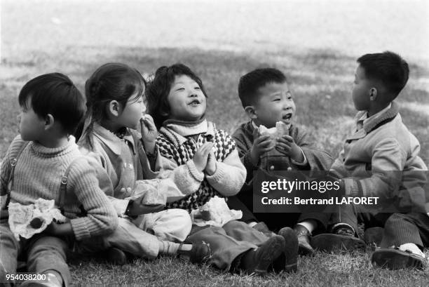 Jeunes enfants entrain de goûter dans un parc en février 1982 à Shanghai, Chine.