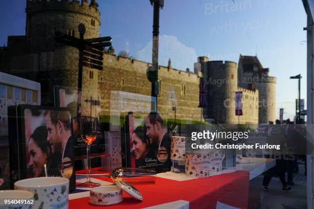 Windsor Castle is reflected in a gift shop window featuring souvenirs of Britain's Prince Harry and his fiance, US actress Meghan Markle, on May 2,...