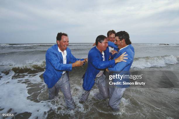 Mark O''Meara and Payne Stewart look on as team captain Dave Stockton pushes Corey Pavin into the water as the USA celebrate on the beach after...