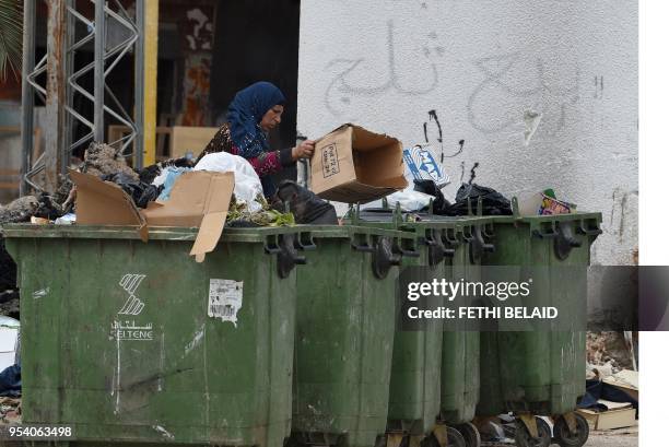Woman searches rubbish bins in a street of Ettadhamen city on April 28 an impoverished area of Greater Tunis. - At the approach of the first...