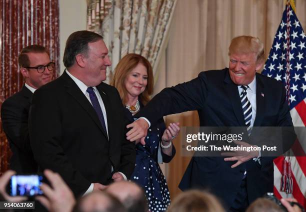 President Donald Trump pats Mike Pompeo on the arm after Pompeo was sworn in as the new Secretary of State while his family Nick, left rear, and...