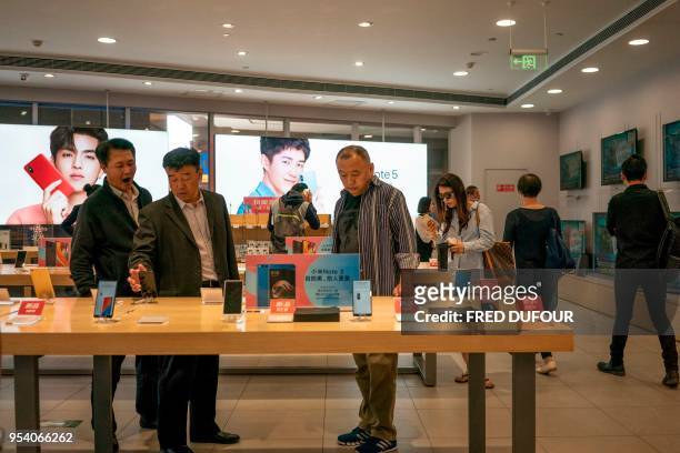 Customers look at Xiaomi smartphones in a shop in Beijing on May 3, 2018. - Chinese smartphone maker Xiaomi has kicked off what is expected to be the...