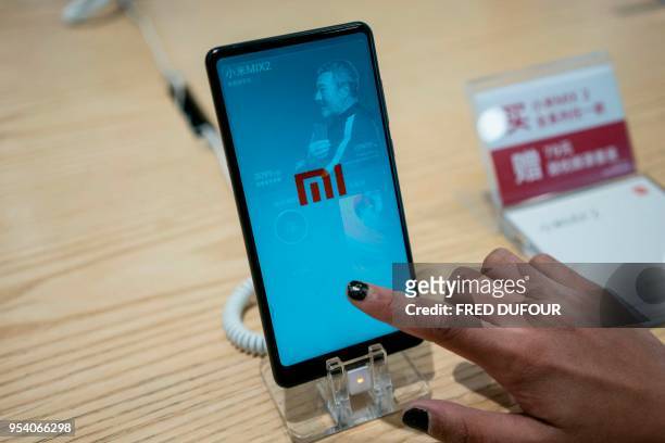Customer looks at a Xiaomi smartphone in a shop in Beijing on May 3, 2018. - Chinese smartphone maker Xiaomi has kicked off what is expected to be...