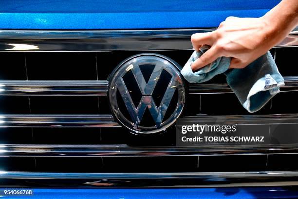 Staff member cleans the logo of a SUV VW Touareg on display ahead of the annual general meeting of German carmaker Volkswagen, in Berlin on May 3,...