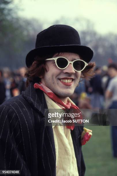 Jeune homme punk portant un chapeau melon, des lunettes de soleil et du maquillage dans les années 1970 à Londres, Royaume-Uni.