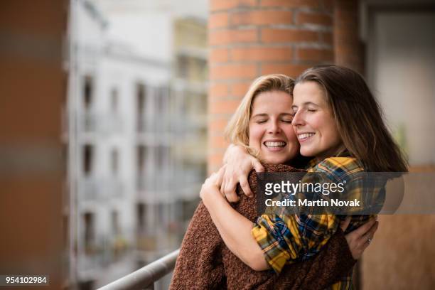 twin sisters embracing each other in balcony - apologize stockfoto's en -beelden