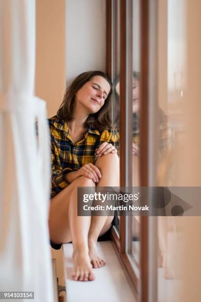 woman relaxing while seated near window - common aims stock-fotos und bilder