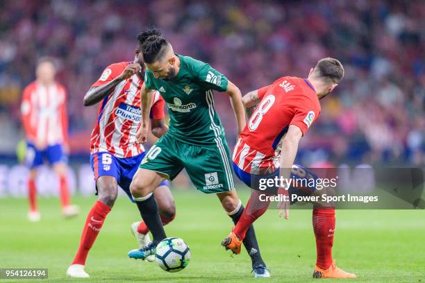 Ryad Boudebouz of Real Betis fights for the ball with Thomas Teye Partey of Atletico de Madrid and Saul Niguez Esclapez of Atletico de Madrid during...