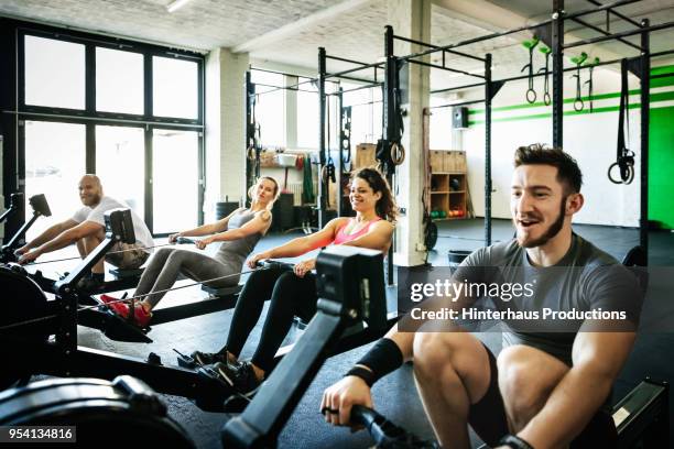 Fitness Group Exercising With Rowing Machines Together