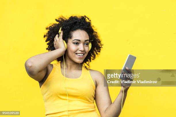 femme africaine avec musique écoute gilet jaune - fashion pretty woman listening music in headphones with smartphone colorful photos et images de collection