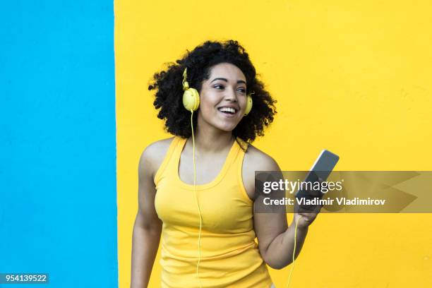 afrikaanse vrouw plezier en muziek luisteren - fashion pretty woman listening music in headphones with smartphone colorful stockfoto's en -beelden