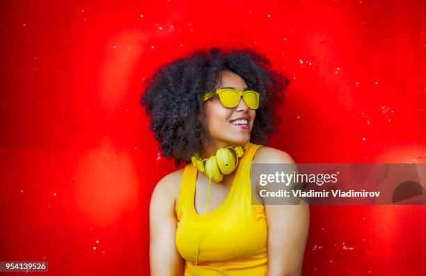 afrikaanse vrouw met gele vest en zonnebril - fashion pretty woman listening music in headphones with smartphone colorful stockfoto's en -beelden