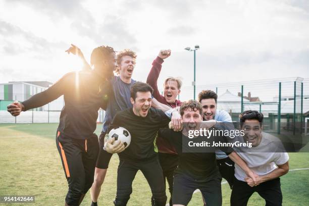 camaraderie among friends cheering after winning football match - urban football pitch stock pictures, royalty-free photos & images