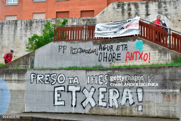 People walk past graffiti claiming ETA's prisoners back home in the Spanish Basque village of Agurain on May 3, 2018. - Spanish Prime Minister...