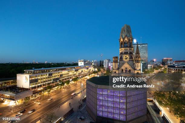 The restored Kaiser Wilhelm Memorial Church, also called the Gedaechtniskirche and the Bikini Berlin shopping center stand illuminated during blue...