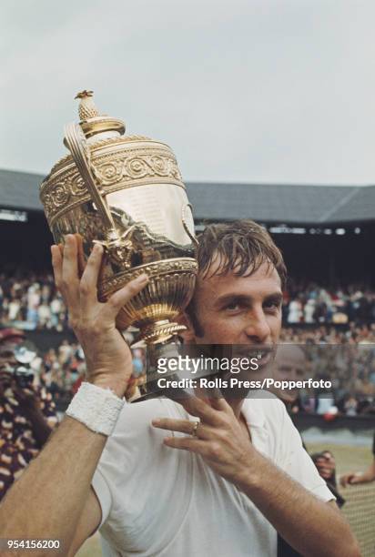 Australian tennis player John Newcombe holds the Gentlemen's Singles Trophy in the air after defeating Ken Rosewall to win the final of the Men's...