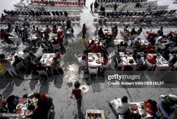 Vue de dessus d'une terrasse de restaurant en plein air sur laquelle des serveurs apportent à manger aux vacanciers attablés en mars 1984 à Val...