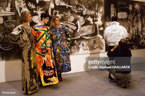 Le peintre Keith Haring accroupi entrain de signer un dessin sur un vêtement lors de la Biennale de Paris en mars 1985, France.