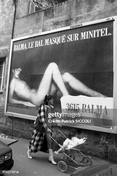 Une jeune femme et sa fille passent devant une affiche publicitaire pour une messagerie rose à Nice en avril 1987, France.