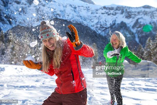 schneeballschlacht im skiurlaub - mature woman winter stock-fotos und bilder