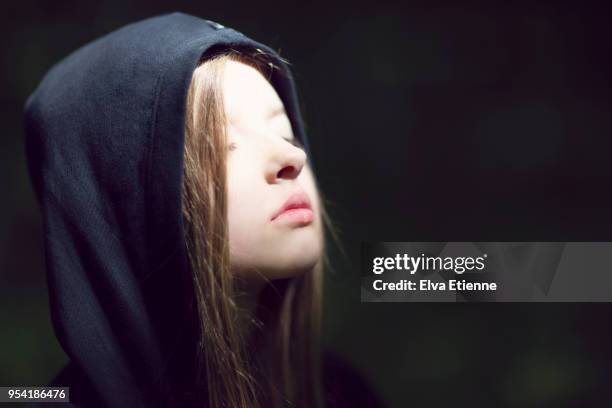 pre-adolescent child wearing hoodie, with head raised towards a patch of sunlight - pre adolescent child bildbanksfoton och bilder