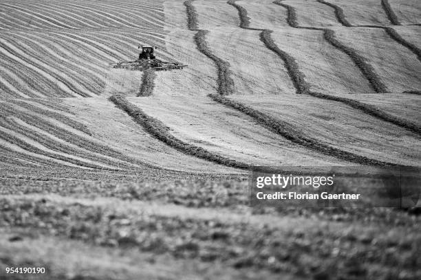 Image has been converted to black and white.) SCHOENAU-BERZDORF, GERMANY A tractor with a windrow is pictured on a field on May 01, 2018 in...