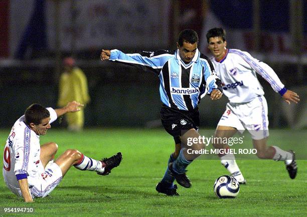 Zinho player from Gremio, takes the ball in front of the mark for the players from Nacional, Andres Scotti and Richard Pellejero, during the game for...