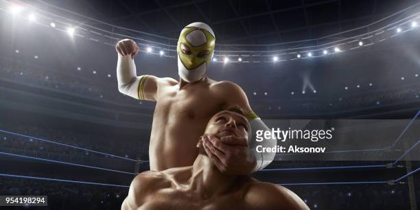 wrestling show. two wrestlers in a bright sport clothes and face mask fight in the ring - prender a cabeça imagens e fotografias de stock