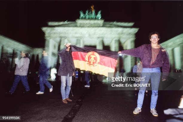 Berlinois montrant un drapeau devant la porte de Brandebourg lors de la chute du Mur de Berlin le 10 novembre 1989, Allemagne.