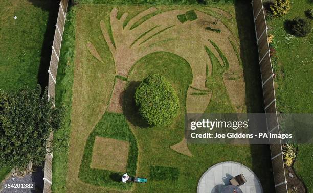 Sue Richards, 51 and 58-year-old Barry Maddox put the finishing touches to their new lawn design of a giant champagne bottle and glasses, at their...