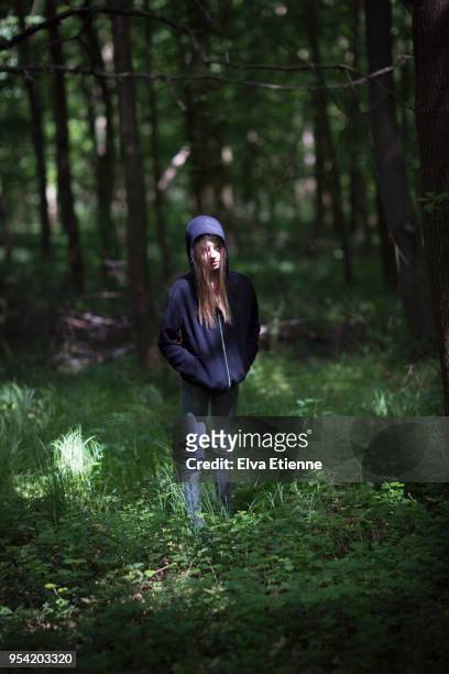 moody pre-adolescent girl standing in dark patch of woodland - pre adolescent child bildbanksfoton och bilder