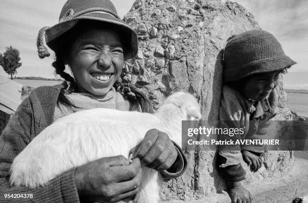 Une jeune fille porte un petit agneau lors des graves inondations près du lac Titicaca en mars 1986, Puno, Pérou.