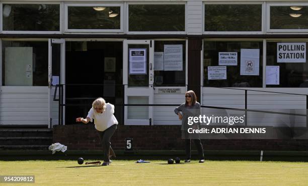 Two women play lawn bowls outside the temporary polling station at Cambridge Park Bowling Club in Twickenham in the Borough of Richmond upon Thames...