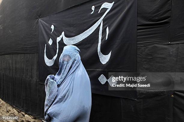 An Afghan woman walks past Shiite religious flags during Ashura on December 27, 2009 in Kabul, Afghanistan. Ashura is a period of mourning in...