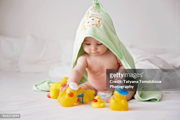 cute little baby toddler boy, playing with rubber ducks after bath in bed - cechy stockfoto's en -beelden