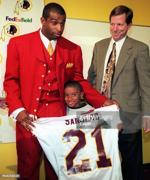 New Washington Redskin cornerback Deion Sanders shows off his jersey with son Deion Jr. And head coach Norv Turner 05 June during a press conference...