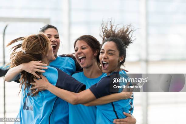 excited female soccer players hugging after scoring a goal - time de futebol imagens e fotografias de stock