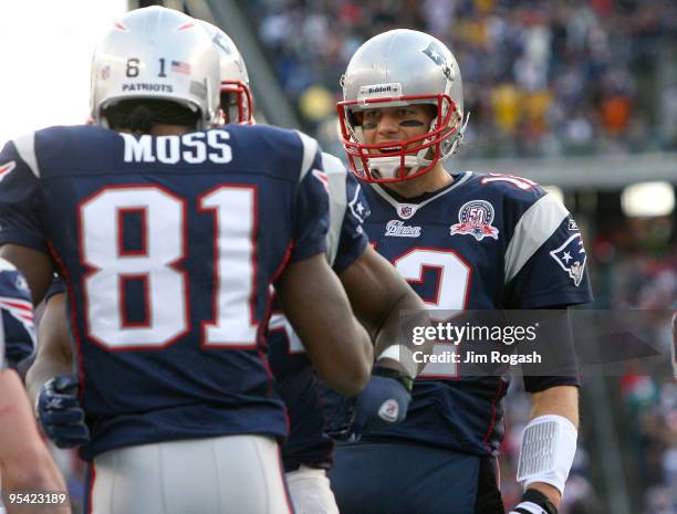 Randy Moss of the New England Patriots is congratulated by team mate Tom Brady after catching his third touchdown pass of the day against the...
