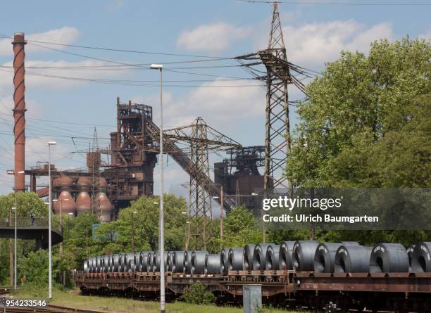 Steel production at ThyssenKrupp in Duisburg. The picture shws rolled sheet/steel sheet on a freight train. In the background a blast furnace.