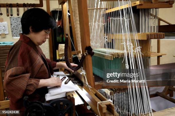 Seamstress weaves a traditional japanese dress in a fabric store on April 18, 2018 in Kyoto, Japan. Kyoto, literally "Capital City", is a city...