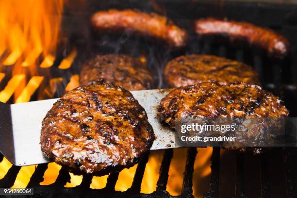 vier hamburgers rundvlees en twee bratwursts op een hete barbecue grill - burger grill stockfoto's en -beelden