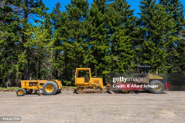 earth movers at road contruction site in forest - schrottpresse stock-fotos und bilder