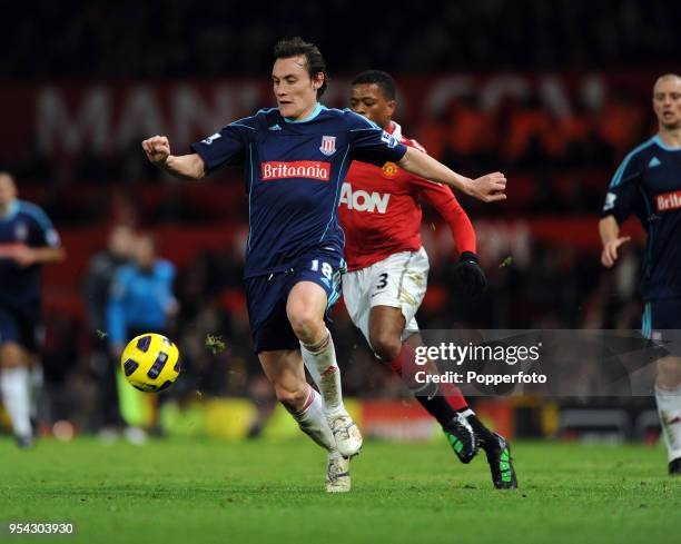 Dean Whitehead of Stoke City is chased by Patrice Evra of Manchester United during the Barclays Premier League match between Manchester United and...