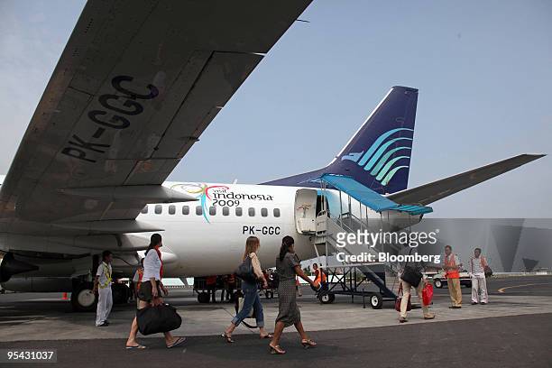 Passengers walk to a PT Garuda Indonesia airplane at Ahmad Yani Airport in Semarang, Indonesia, on Thursday, Dec. 24, 2009. PT Bank Mandiri said it...