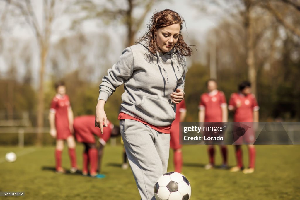 Young redhead Female Soccer Coach with her male Football team