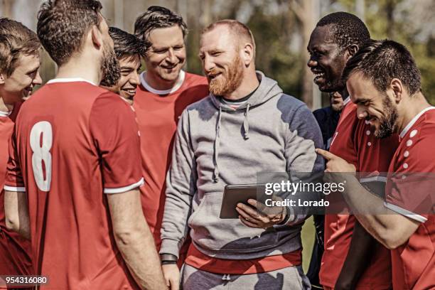 een voetbalteam kijken tactiek op een tablet tijdens een trainingssessie voetbal met de coaching team - mens soccer team training session stockfoto's en -beelden