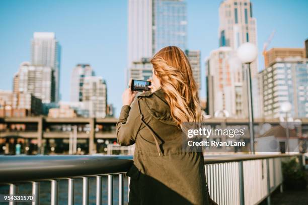 woman takes smart phone picture of downtown seattle - seattle city life stock pictures, royalty-free photos & images