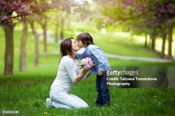 beautiful kid and mom in spring park, flower and present. mothers day celebration concept - giving a girl head stock pictures, royalty-free photos & images