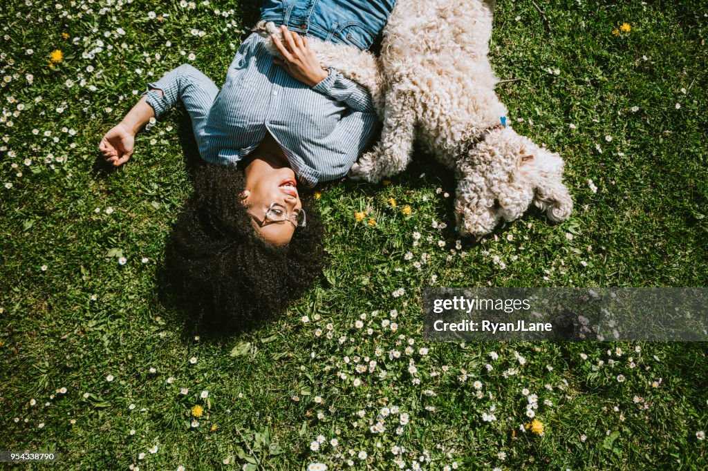 A Young Woman Rests in the Grass With Pet Poodle Dog